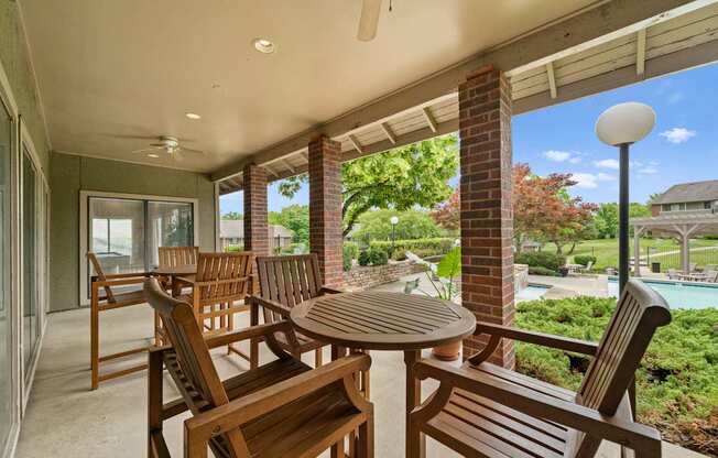 A patio with a table and chairs overlooking a pool.