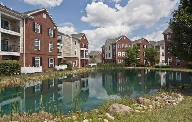 A row of apartment buildings are reflected in a body of water.