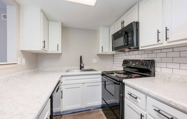 a kitchen with white cabinets and a black stove and microwave