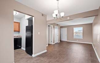 an empty living room and kitchen with a black refrigerator