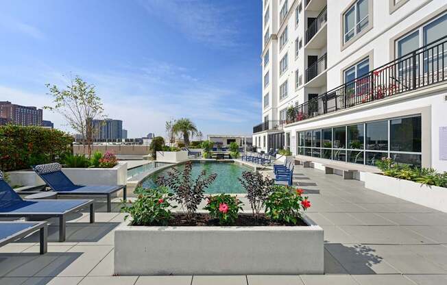 Our rooftop pool with a planter box with flowers and chairs at Dominion Post Oak apartments in Houston, TX