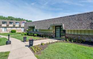 the front of a building with a sidewalk and grass