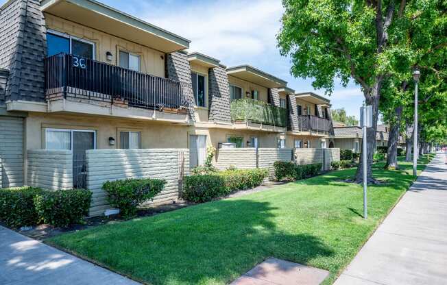 a row of apartments with balconies and green grass and trees