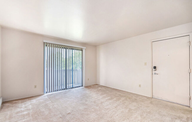 spacious living room with a sliding glass door to a balcony at West Wind Apartments in Fort Wayne, IN