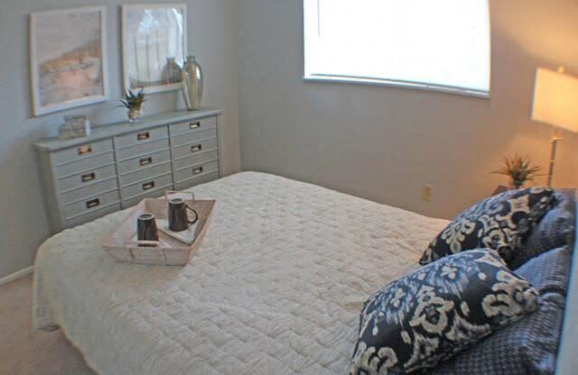 a bedroom with a bed, dresser, and a window