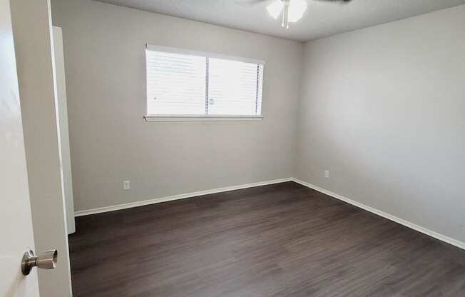 an empty living room with wood floors and a ceiling fan