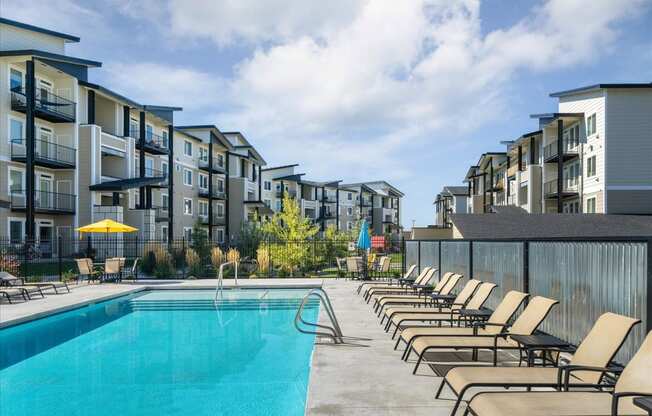 a swimming pool with lounge chairs next to an apartment building