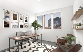 Home office with a desk and a window and a wall of framed photos