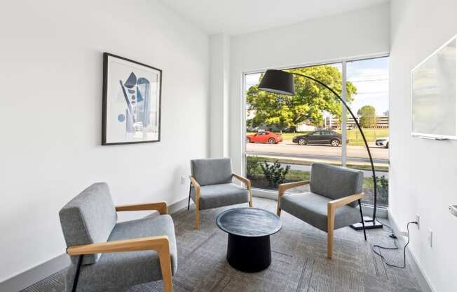 A living room with a grey sofa, a grey armchair, a black coffee table and a picture on the wall.
