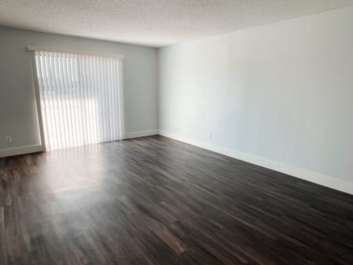 an empty living room with wood floors and a window