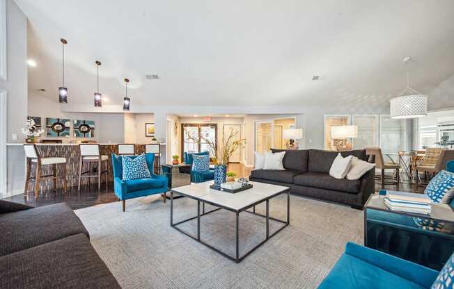 A modern living room with a black couch, blue chairs, and a white coffee table.