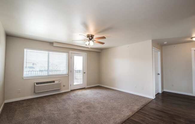 an empty living room with a ceiling fan and a window