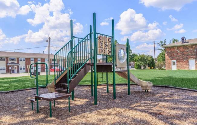 a playground with a slide and stairs in front of a building