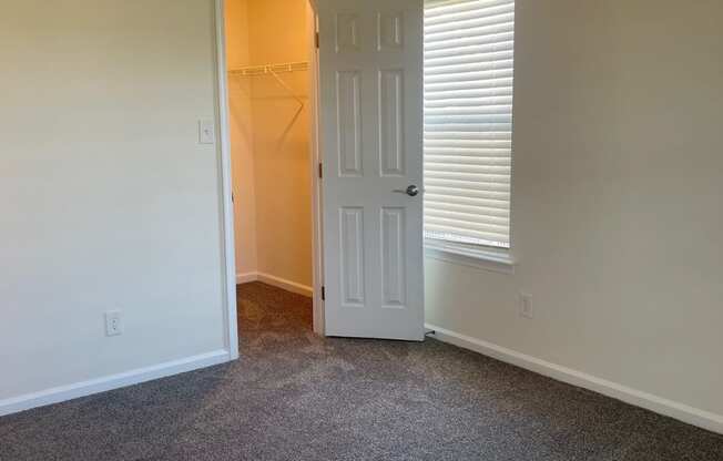 an empty living room with a door to a closet