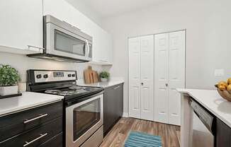 A modern kitchen with a black stove top oven and a silver microwave above it.