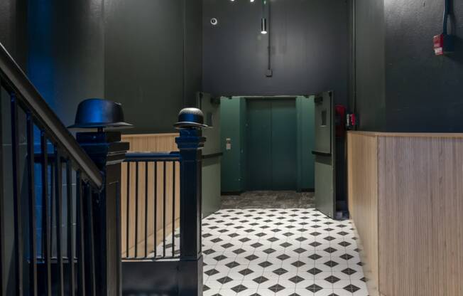 a hallway with a black and white tiled floor and a green door at The Draper, St Louis, MO