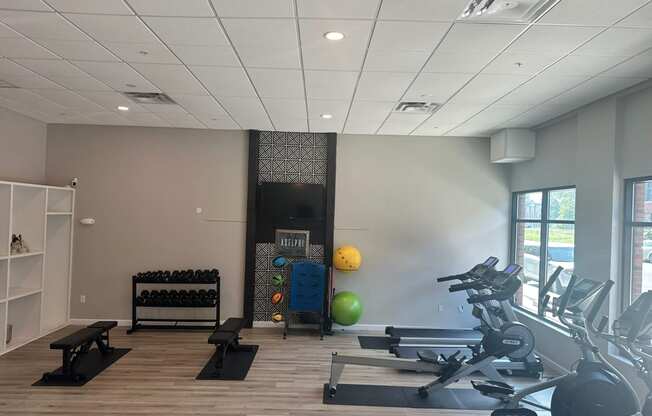 a gym with weights and other exercise equipment in a building with windows