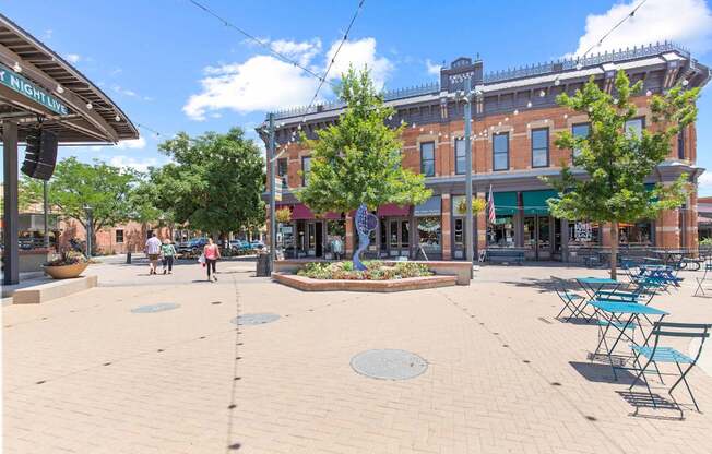 A sunny day in a town square with people walking and a building with a sign that says "The High Line".