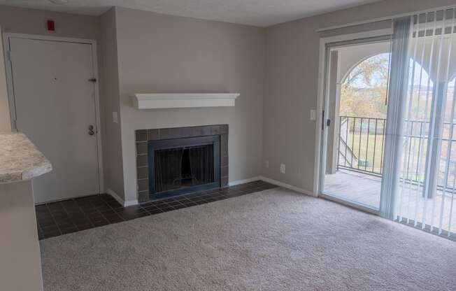 an empty living room with a fireplace and a patio door