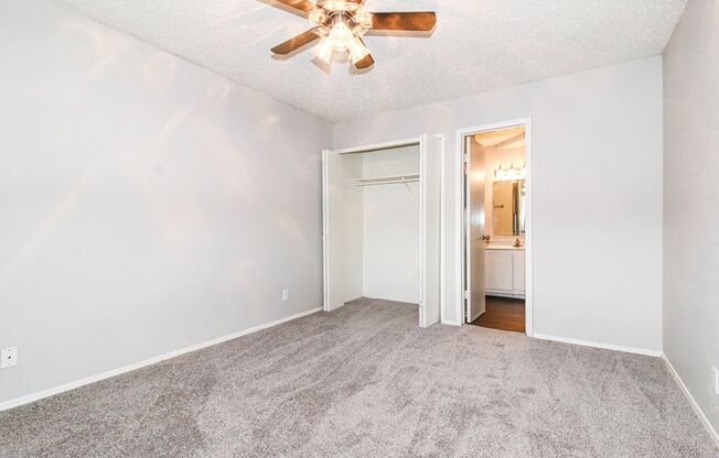 an empty living room with a ceiling fan