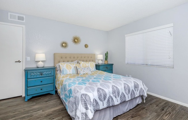 A bedroom with a blue bed and a white wall.