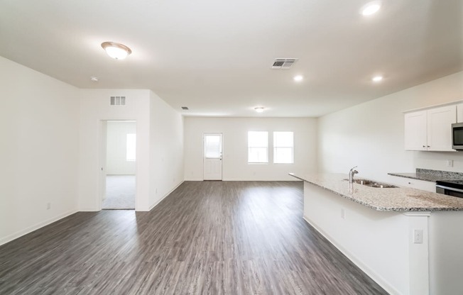 the modern living room and kitchen with white walls, windows a granite countertop