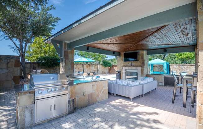 a covered outdoor kitchen with a grill and a pool