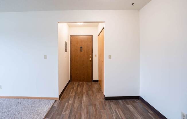A room with a wooden door and floor. West Fargo, ND Saddlebrook Apartments