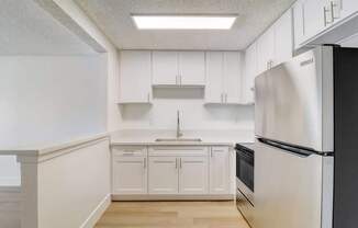 A kitchen with white cabinets and a black refrigerator.