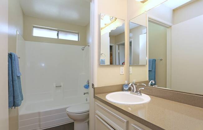 A bathroom with a white toilet, sink, and a blue towel.