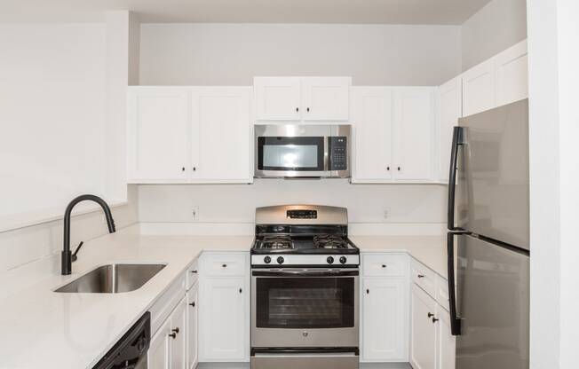 a kitchen with white cabinets and stainless steel appliances