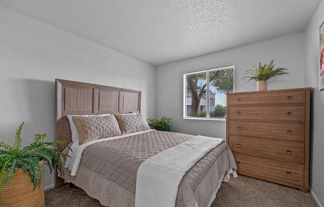 A bedroom with a bed, dresser, and window.