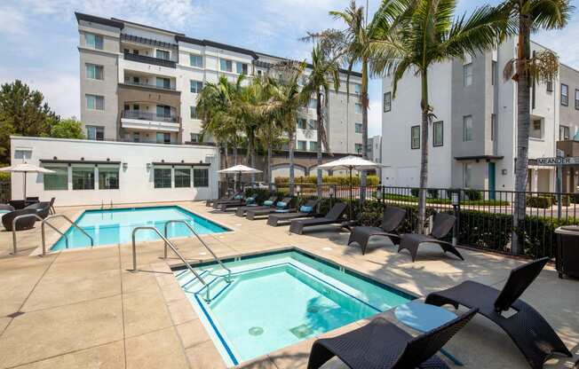A large swimming pool surrounded by lounge chairs and palm trees.