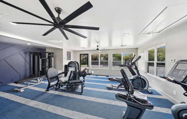 a gym with exercise machines and a ceiling fan