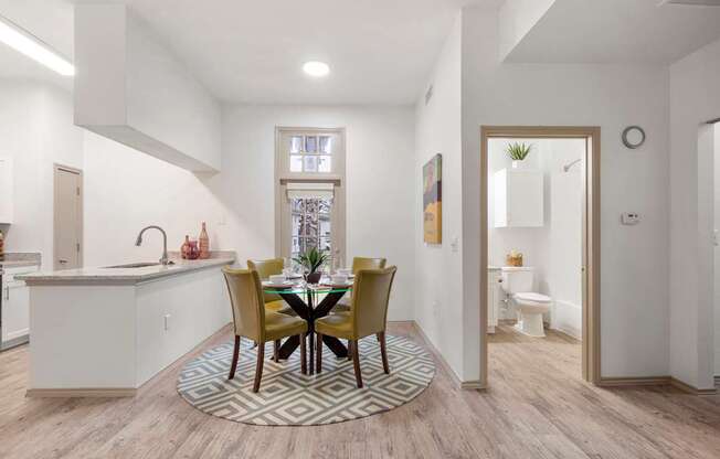 A kitchen with a dining table and chairs in the middle.