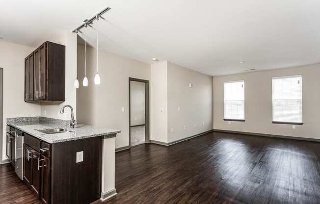 an empty living room and kitchen with wood flooring and a counter top