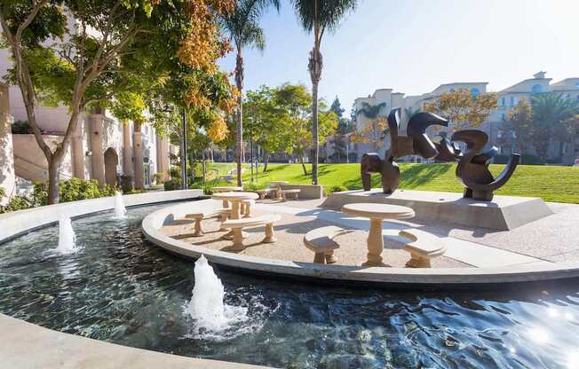A fountain in the middle of a park with a sculpture in the background. at La Jolla Crossroads Apartments, California