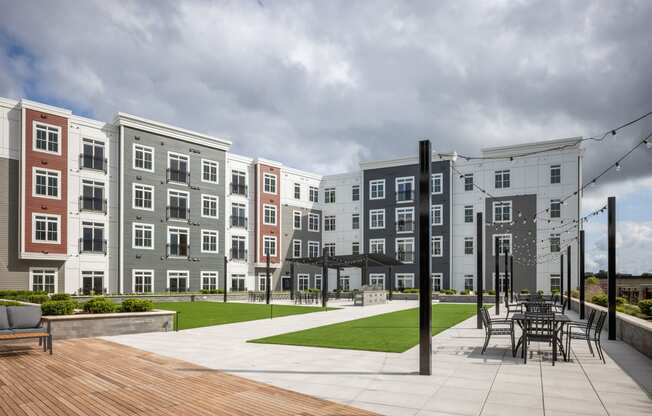 an exterior view of an apartment building with a patio and lawn