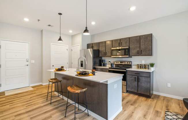 an open kitchen with a large island with three stools at EagleRidge Plaza Residences, North Dakota, 58104