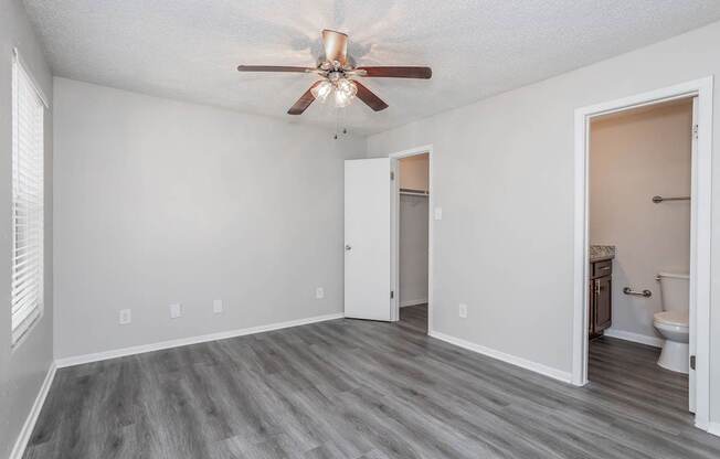 A room with a ceiling fan and a toilet in the corner.