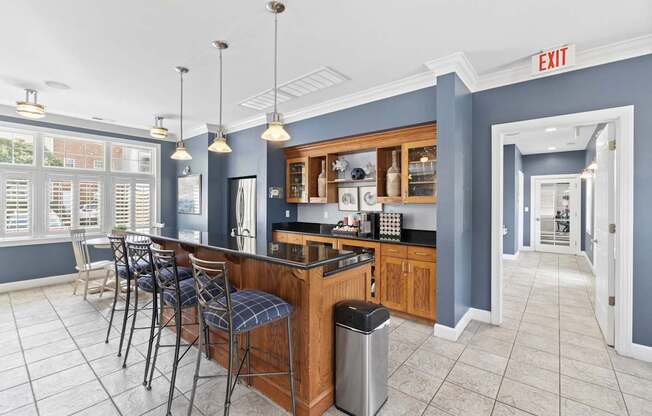 a communal kitchen with a bar and chairs in a lobby