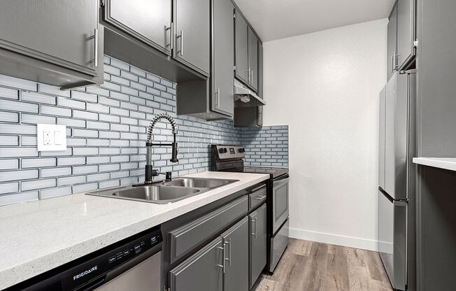 White tiled kitchen with stainless steel fridge, microwave, and oven.