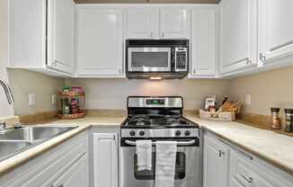 A kitchen with white cabinets and a black microwave above the stove.