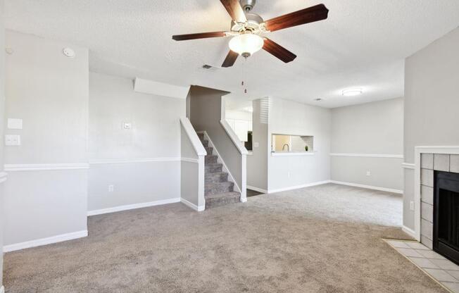 an empty living room with a ceiling fan and a fireplace