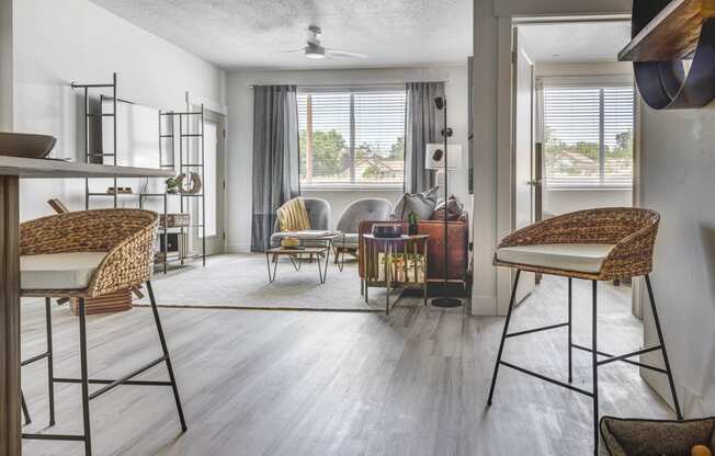 Shot of apartment living room with wood tone floors, designed furnishings, and large windows