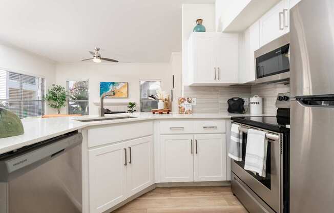 A modern kitchen with white cabinets and stainless steel appliances.