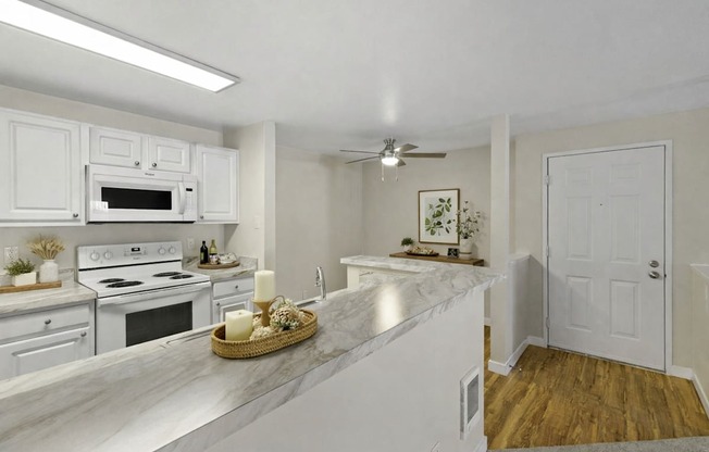 A kitchen with white cabinets and a marble countertop.