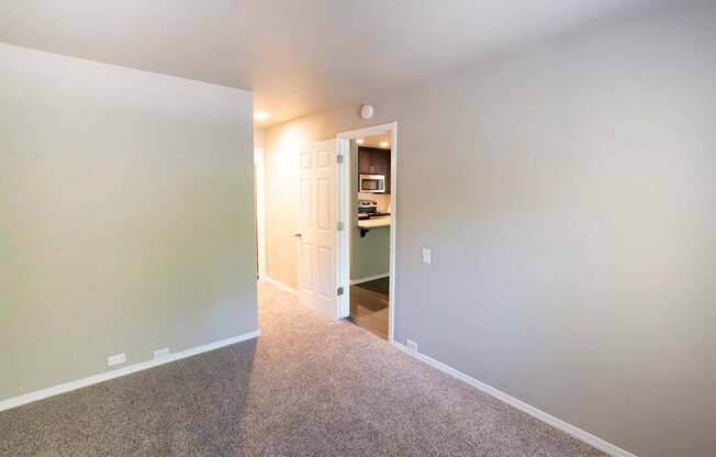 A room with a carpeted floor and a doorway leading to another room.