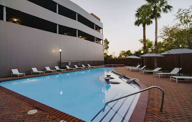A swimming pool surrounded by lounge chairs and umbrellas.