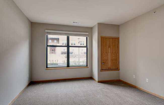 an empty living room with a large window and a wooden door